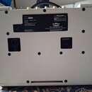 Zadní strana kytarového komba v bílém vinylu. Na zadním panelu jsou dvě štítky, z nichž jeden obsahuje text Model No. AC10C1 a Serial No. PD70586, dá…