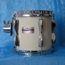 Bílý buben s chromovaným kováním a obručemi. Na korpusu je nalepený štítek s nápisy YAMAHA, MODEL RECORDING a MADE IN JAPAN. Povrch nástroje i kování…
