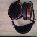 Černá sluchátka s mušlemi z hnědého dřeva a černým polstrovaným náhrobkem. Na vnější straně mušle je bílý nápis PLANAR MAGNETIC TECHNOLOGY a Audeze L…