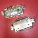 Dvě elektrické kytarové snímače v zlatavém kovovém provedení. Na horním je nálepka s nápisem 498 T, 860-30926-L a datem 01/18/19. Spodní snímač má na…