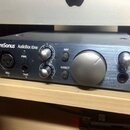 Stříbrný audio rozhraní s nápisem PreSonus AudioBox iOne. Na přední straně jsou umístěny dva otočné knofíky, tlačítka 48V a DIRECT, vstup Mic 1, vstu…