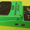 Zelený kytarový efekt s černým ovládacím panelem a černým spínacím tlačítkem. Na horní straně je nápis VINTAGE TUBE OVERDRIVE a model TO800, vlevo je…