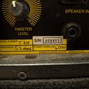 Detail zadní strany basového reproduktoru s ovládacím knoflíkem TWEETER LEVEL a dvěma vstupy SPEAKER INPUT/OU. Na žlutém štítku je uveden MODEL NUMBE…