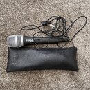 Černý dynamický mikrofon s kovovou stříbrnou mřížkou a připojeným kabelem. Na těle mikrofonu je bílý nápis iRig Mic. Součástí je černý kožený nebo sy…