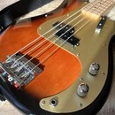 Elektrická basová kytara s tělem v provedení sunburst a zlatým plecháčem. Na instrumentu jsou vidět dva chromované ovládací knofíky a jedna zásuvka.…