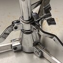 Detail spodní části chromovaného stojanu s rozkládacími nohama. Na kovovém povrchu jsou viditelné drobné škrábance a známky opotřebení. Stojan je vyb…