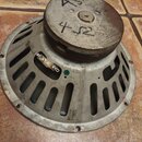 Fotografie zachycuje zadní stranu reproduktoru s kovovým rámem a hnědým magnetem. Na magnetu je ručně napsáno 4Ω, na rámu je nápis 12MG-T 465-138. Po…