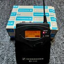 Černý bezdrátový vysílač s displejem, na kterém je text 517.875MHz Y LUDEK01 a indikátor baterie. Na spodní části je bílý nápis SENNHEISER ew 100 G3.…