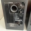Zadní strana černého aktivního reproduktoru značky YAMAHA s nápisem POWERED SPEAKER SYSTEM MODEL HS7. Jsou zde vidět ovládací prvky LEVEL, ROOM CONTR…