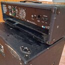 Zadní strana kytarového zesilovače značky Marshall v černém texturovaném potahu. Jsou vidět konektory, ventilátor a nápisy „EFFECTS LOOP“, „FOOTSWITC…