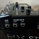 Černý kytarový efekt s nápisem LINE 6 HX STOMP. Na zadní straně jsou tři konektory s popisky SEND STEREO, RETURN / AUX IN L/MONO a RIGHT. Na horní st…