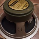 Reproduktor s olivově zeleným magnetem a béžovým rámem. Na horní straně magnetu je žlutá nálepka s nápisy Celestion, Model number G12 H, Power capaci…