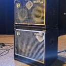 Dvě černé basové reproduktorové skříně naskládané na sebe. Horní skříň má stříbrnou mřížku s nápisy GOLIATH III a 8 OHM a logem značky Warwick. Spodn…