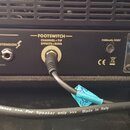 Zadní panel kytarového zesilovače s připojenými kabely. Jsou zde viditelné nápisy SPEAKER, IMPEDANCE (4 Ω, 8 Ω, 16 Ω), MAIN (USE FIRST), EXTENSION a…