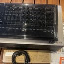 Na fotografii je černý syntezátor Roland SH-4d v originálním plastovém obalu, umístěný na své krabici. Nástroj má numerous otočné knoflíky, posuvníky…