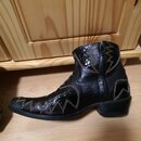 Černá kožená bota typu cowboy s výraznou strukturou kůže a ozdobným prošíváním. Bota má zip na vnitřní straně kotníku a špičatý tvar. Na povrchu nejs…