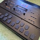 Černý sampler s připojeným externím kontrolérem s gumovými pady. Na horním panelu je vidět nápis ASR v růžové barvě a řada tlačítek, posuvníků a malý…