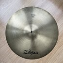 Kruhový činely v zlatavé barvě s viditelným koncentrickým broušením povrchu. Na činely jsou černé nápisy Zildjian a MEDIUM RIDE 18"/46cm. Povrch vyka…