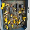 Fotografie zachycuje vnitřek elektronického zařízení s plošným spojem a osazenými součástkami. Na čipech jsou viditelné nápisy MN3005, MN3101, NE557N…