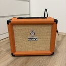 Kytarový kombo zesilovač s oranžovým texturovaným povrchem a béžovou přední síťovkou. Na mřížce je umístěno logo ORANGE a nad ním kulatý štítek s neč…