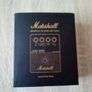 Černá krabice s nápisem Marshall a podtitulem INSPIRED BY THE ICONIC AMP SERIES. Na povrchu je grafický znázornění ovládacích prvků s popisky GAIN, S…