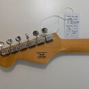 Zadní strana hlavy kytary z přírodního dřeva s chromovanými ladičkami. Na dřevě je nápis „Designed and Backed by Fender“, pod ním sériové číslo „s/n…