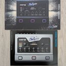 Fotografie zobrazuje dvě varianty kytarového zesilovače značky BluGuitar s nápisem AMP 1. Horní verze je označena jako IRIDIUM EDITION a má černé pro…