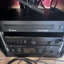 Tři černé audio komponenty v rackovém stojanu. Horní zařízení má nápisy TL Audio a Power Supply, doprava je vypínací spínač POWER. Prostřední přístro…