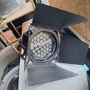 Černý LED reflektor s nastavitelnými klapkami (stínidly) kolem světelného zdroje. Uvnitř jsou viditelné početné malé LED diody uspořádané v hexagonál…