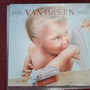 Fotografie zobrazuje obal CD s albem skupiny VAN HALEN. Na přední straně je zobrazen malý křídlatý chlapec s cigaretou v ruce a krabičkou cigaret pře…
