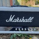 Kytarový kombo zesilovač v šedém vinylovém potahu s černou mřížkou, na které je bílý nápis Marshall. Spodní ovládací panel obsahuje červený vypínač,…