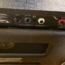 Zadní panel kytarového zesilovače s černým povrchem. Jsou zde viditelné nápisy „TRIODE (Half Power)“, logo „Marshall“, text „Designed, Engineered & Q…