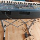 Černý digitální klavír značky YAMAHA umístěný na stříbrném X-kovém stojanu. Na ovládacím panelu jsou viditelné nápisy VOX, YAMAHA a různé popisky fun…