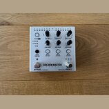 Stříbrný efektový pedál s nápisem GOLDEN MASTER PEDAL a doplňkovým textem 24 BIT 96 KHZ. Zařízení má několik otočných potenciometrů s popisky VU IN O…