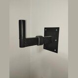 Černý nástěnný držák na hudební nástroj vyrobený z kovových trubek a ploché základny. Horní část je potažena černým materiálem, podobně jako opora v…