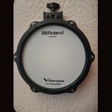 Elektronický buben s bílým mesh povrchem a černým rámem. Na horní části je nápis Roland MESH HEAD a v dolní části V-Drums s doplňkem Patent: roland.c…
