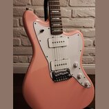 Růžová elektrická kytara s bílým pickguardem a dvěma bílými snímači typu single-coil. Nástroj má hnědý hmatník a stříbrný most s saddles. Na bílých o…