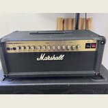 Černý kytarový kombozesilovač s nápisem Marshall na předním textilním krytu. Horní ovládací panel je stříbrný s nápisy JCM600 VALVE GUITAR AMPLIFIER,…