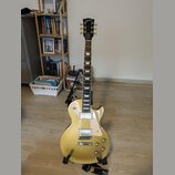 Elektrická kytara s tvarem singlecut, zlatavě žlutým lakem a hnědým hmatníkem. Na hlavě je bílý nápis Gibson. Nástroj má dva humbuckery, čtyři ovláda…