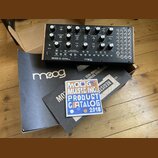 Semi-modulární analogový syntetizátor v dřevěném šasi s černým ovládacím panelem. Na přední straně je nápis MOTHER-32 SEMI-MODULAR ANALOG SYNTHESIZER…