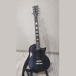Elektrická kytara s černým povrchem z karbonového vlákna. Na hlavě hmatníku je svisle napsaný bílý nápis "KART". Nástroj má dva humbuckery, jeden ovl…