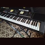 Černý digitální klavír umístěný na černém stojanu s nápisem STIM. Na ovládacím panelu je viditelné logo Roland a nápis XPS-10. Nástroj má bílé a čern…