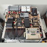 Fotografie zachycuje efektový pedalboard v hliníkovém kufru. Na desce je umístěno několik pedálů s nápisy MORNINGSTAR MIDI CONTROLLED SWITCHER, tc el…