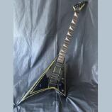 Černá elektrická kytara s tělem ve tvaru V a žlutými konturními pruhy. Na hlavě hmatníku je bílý nápis Jackson. Nástroj má dva humbuckery, dva ovláda…