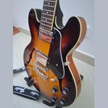 Elektrická kytara s polodupatým korpusem v barevném přechodu od žluté přes oranžovou k hnědé s krémovým lemováním. Nástroj má dva humbuckery, černý p…