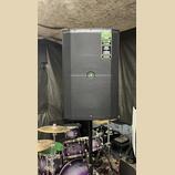 Černý reproduktor s mřížkou, umístěný na stojanu. V pravém horním rohu je zelený štítek s nápisy TRUMP SERIES, 1400W OF POWER, MUSIC DUCKING a FEEDBA…
