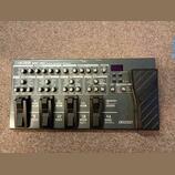 Šedý multifektoped Boss ME-80 Guitar Multiple Effects. Zařízení obsahuje řadu ovládacích knofíků, přepínačů a čtyřistupňové displeje s nápisy jako PR…