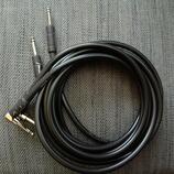 Černý instrumentální kabel s konektory typu 6,35 mm jack. Na jednom z konektorů je bílý nápis Fender a na kabelu se nachází bílá značka A20219. Kabel…