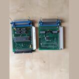 Dvě zelené elektronické desky s modrými konektory a integrovanými obvody. Na levé desce jsou nápisy L601605010, 08860.27 a 1280-064PZX-L1-4N. Na prav…