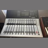 Digitální mixážní pult stříbrné a černé barvy. Na horním černém panelu je nápis YAMAHA a model TF3, dále displej a ovládací prvky. Spodní stříbrná čá…
